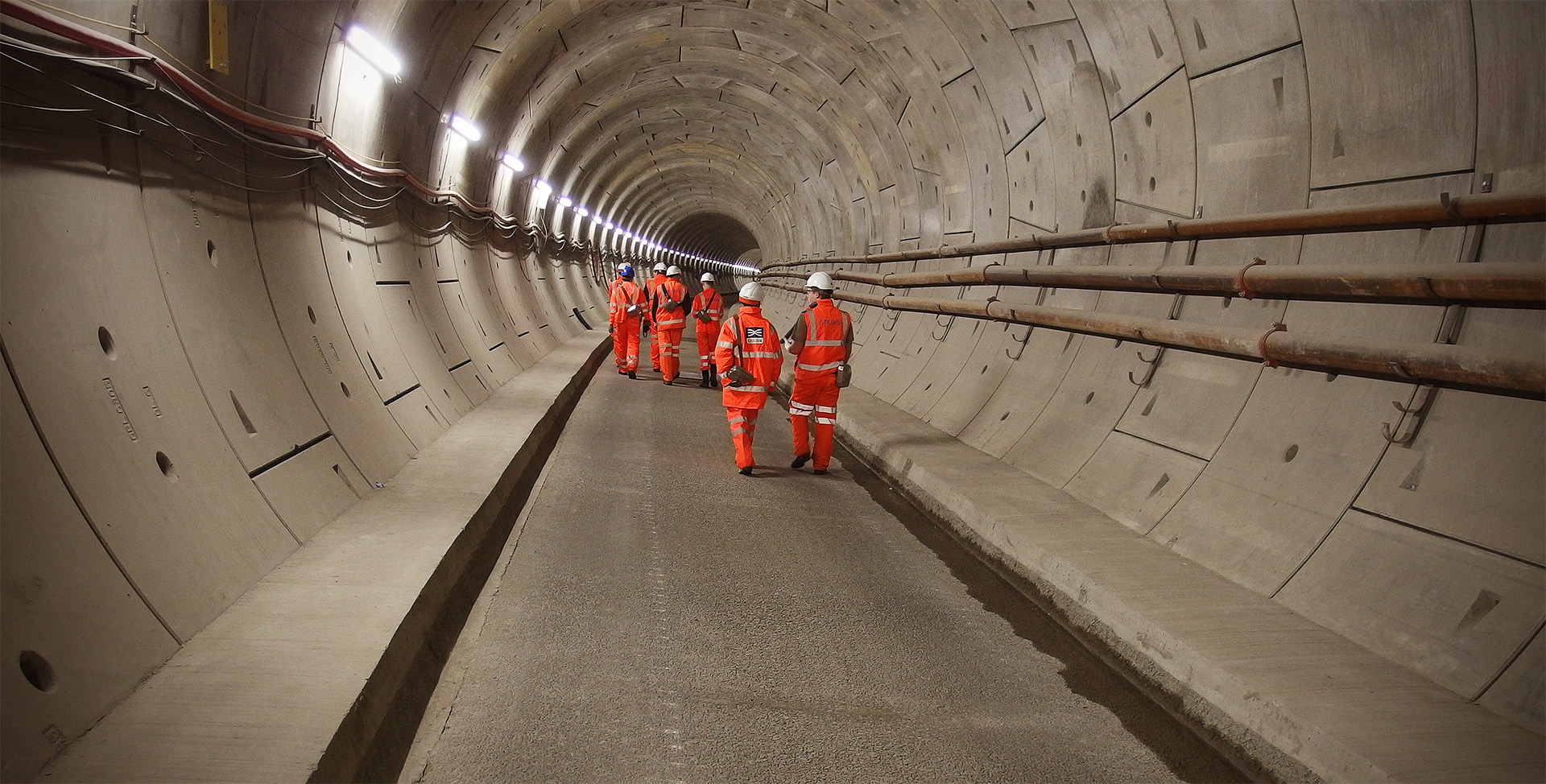 People in orange clothing walk through a tunnel>
		</div>

		<div class=