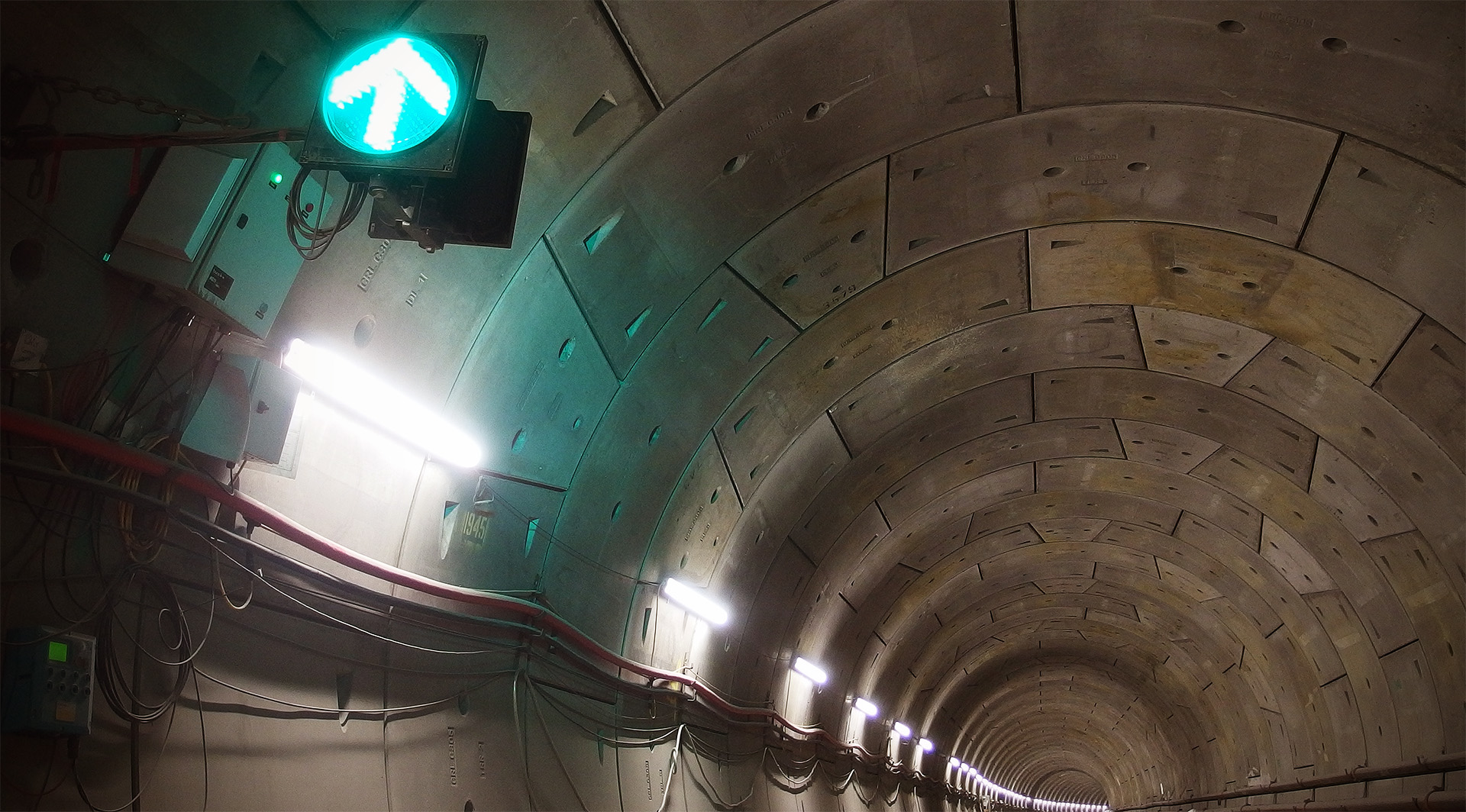 A green light with an arrow is illuminated and mounted on the tunnel wall
