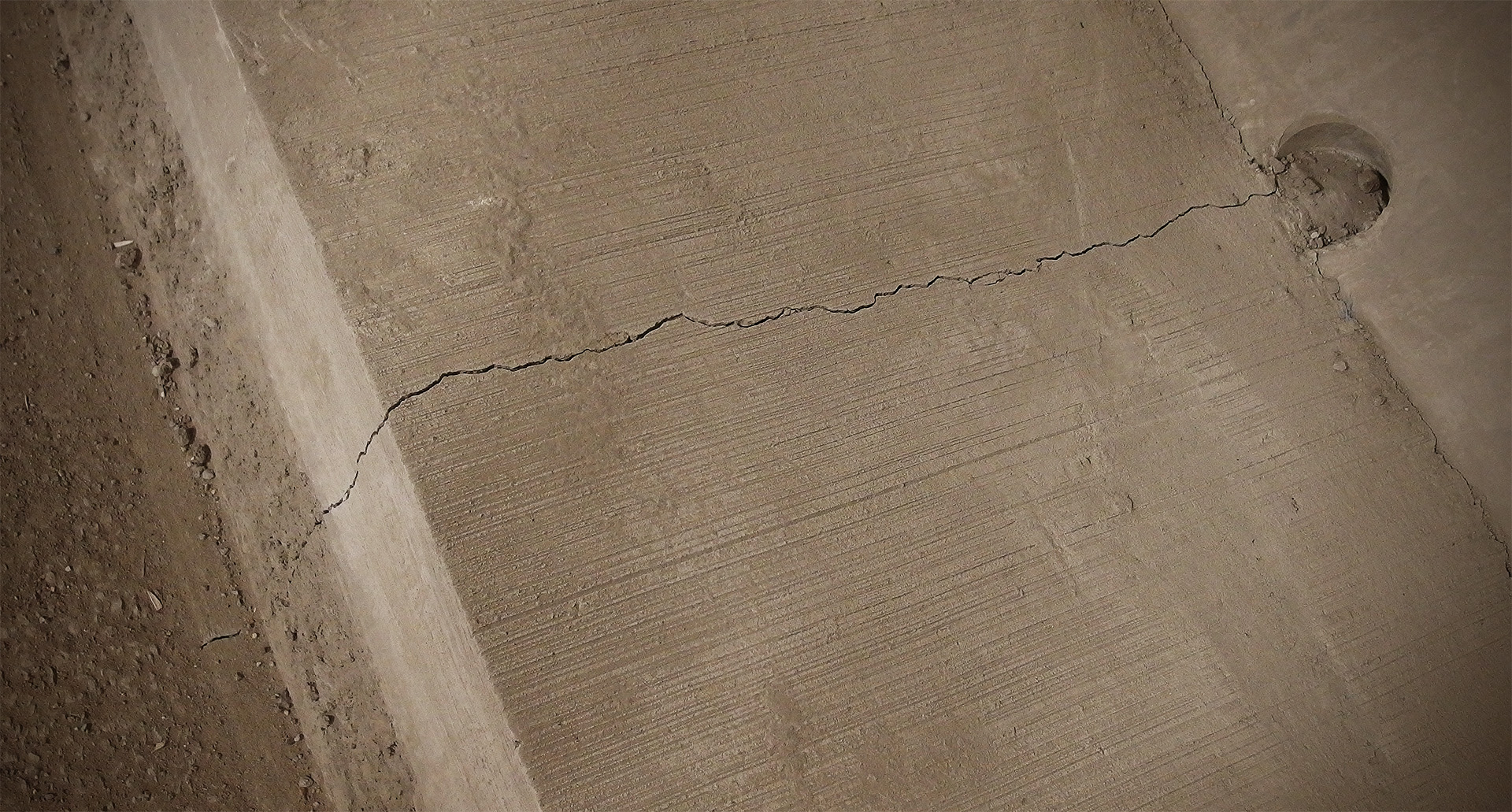 A concrete slab has a thin crack along its width