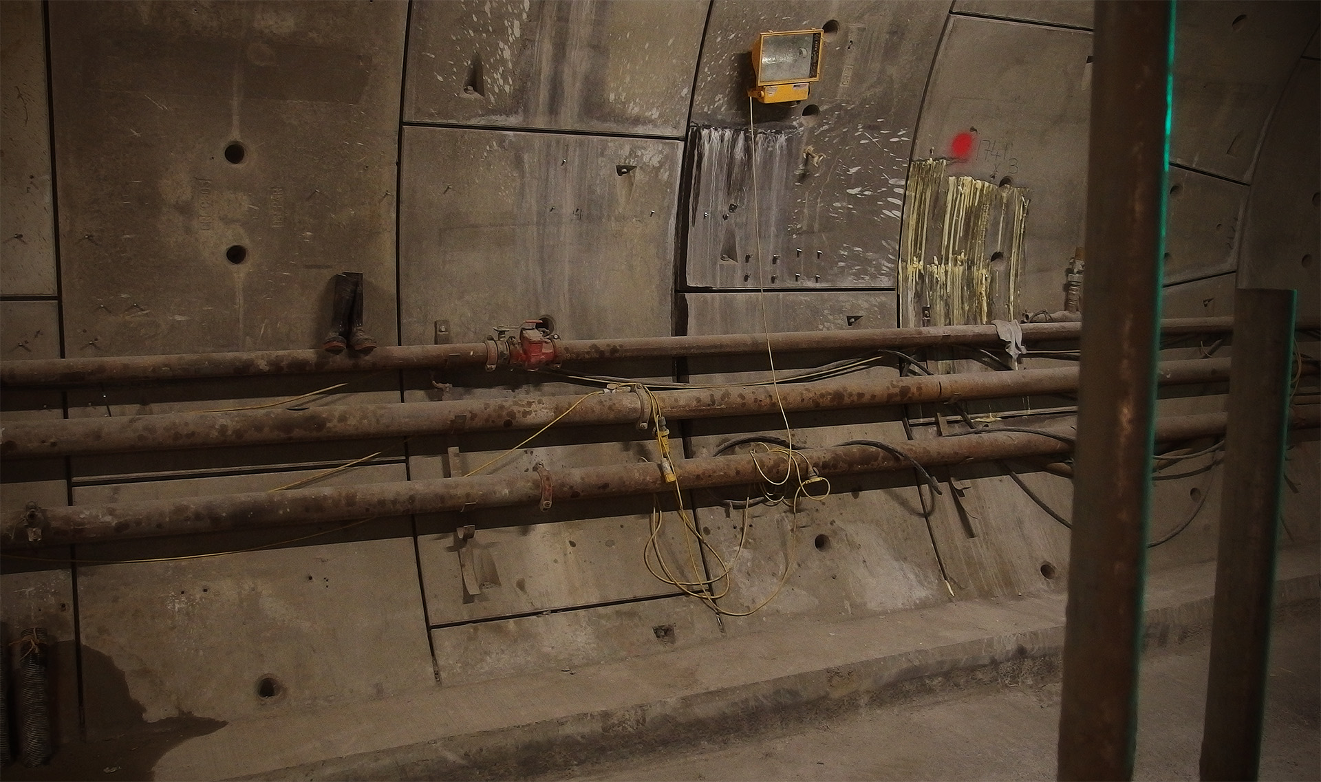 A pair of boots is sat on pipes mounted to the tunnel wall