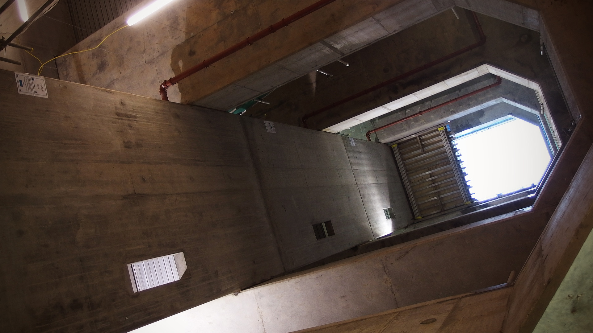 A view up through a concrete shaft to the bright sky above