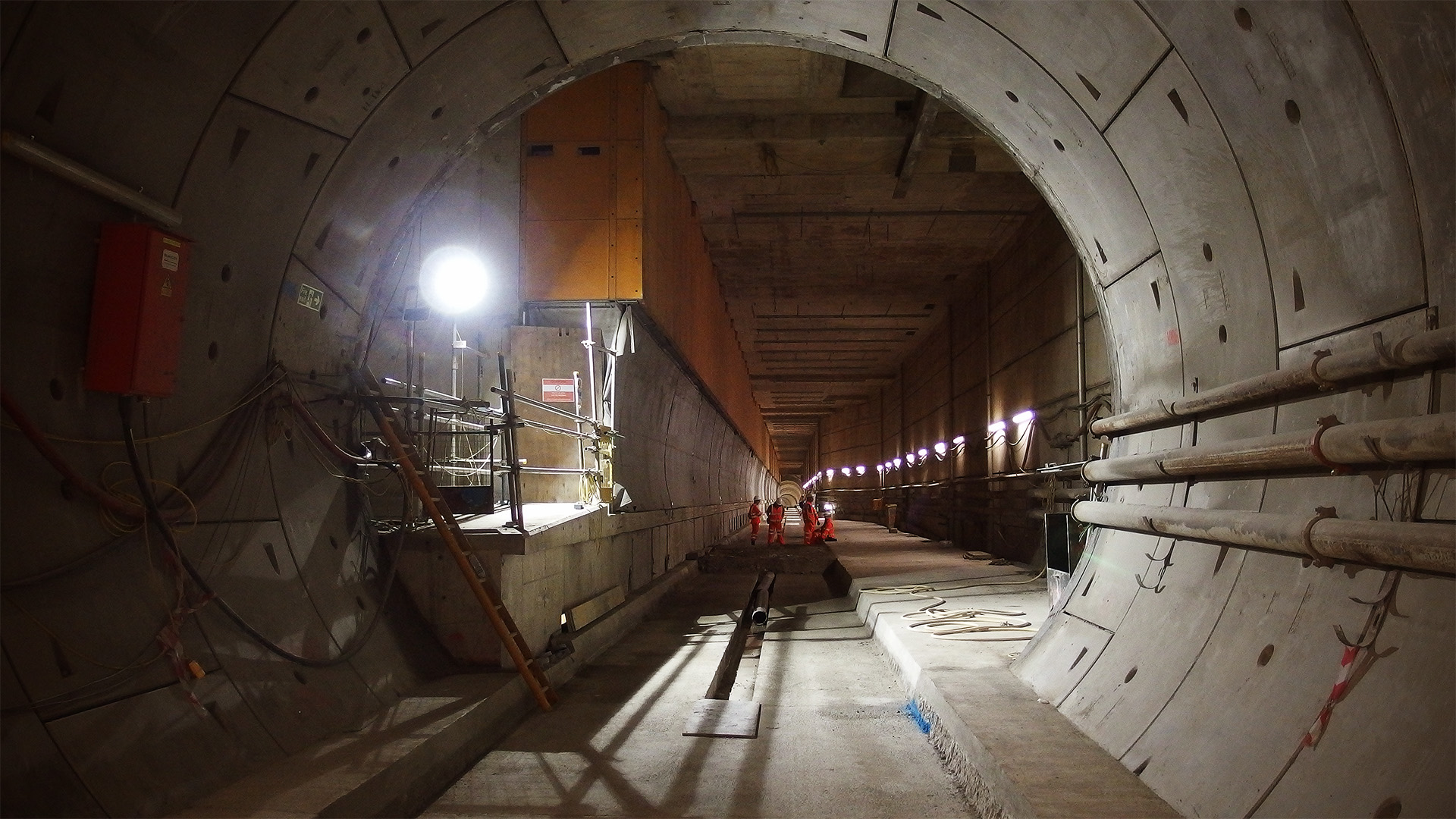 An underground concrete station complex is visible beyond a tunnel portal